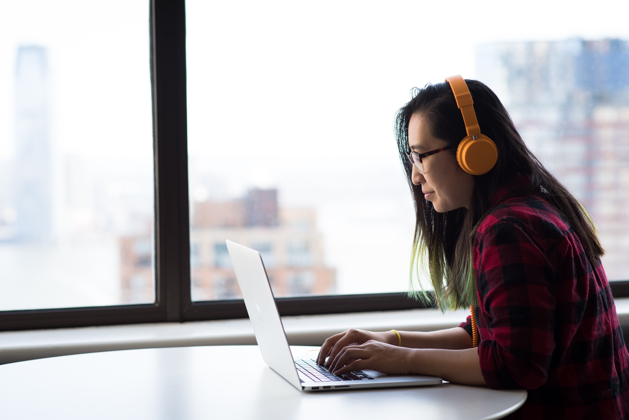 woman wearing headphones, working at a laptop